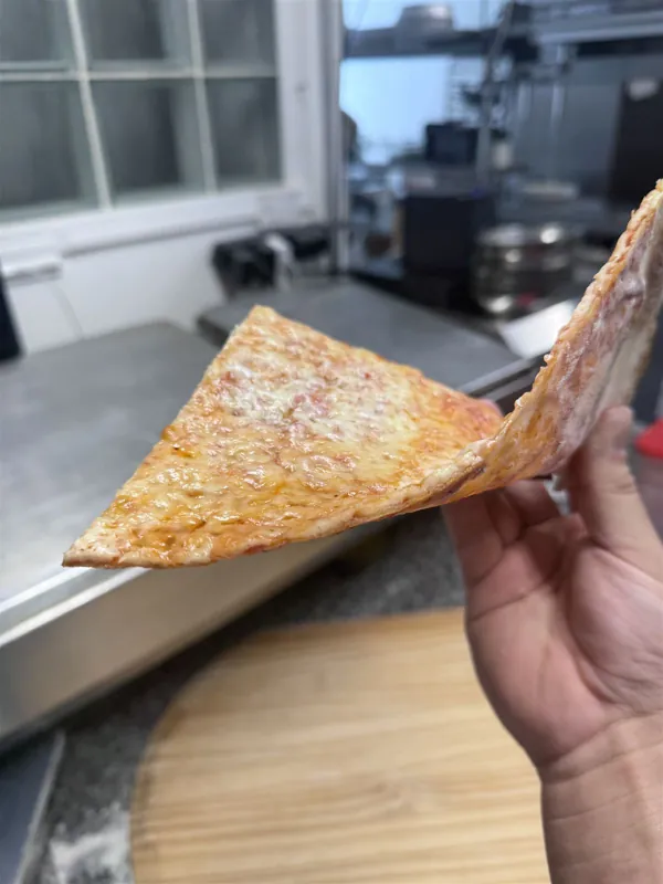 A hand folding a thin New York style cheese slice